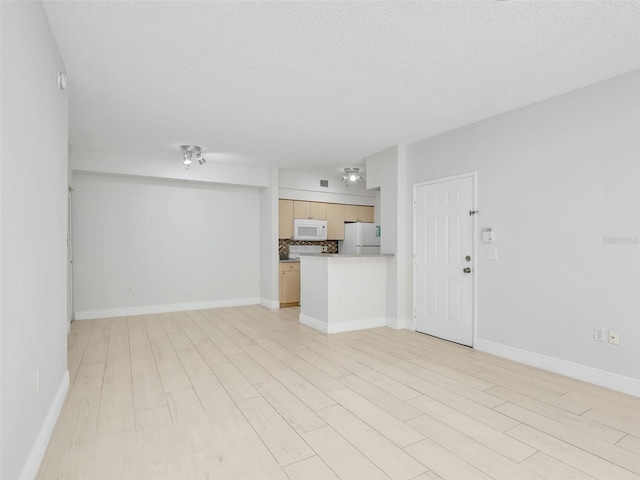 unfurnished living room featuring light hardwood / wood-style flooring and a textured ceiling