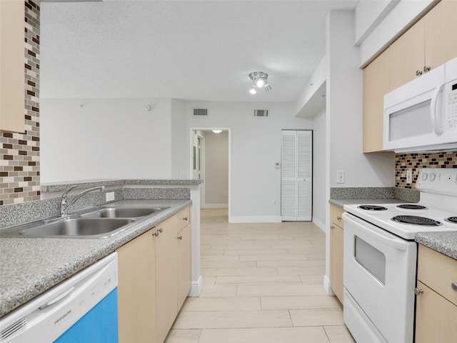 kitchen with sink, tasteful backsplash, a textured ceiling, light brown cabinets, and white appliances