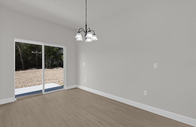 spare room with hardwood / wood-style flooring and a notable chandelier