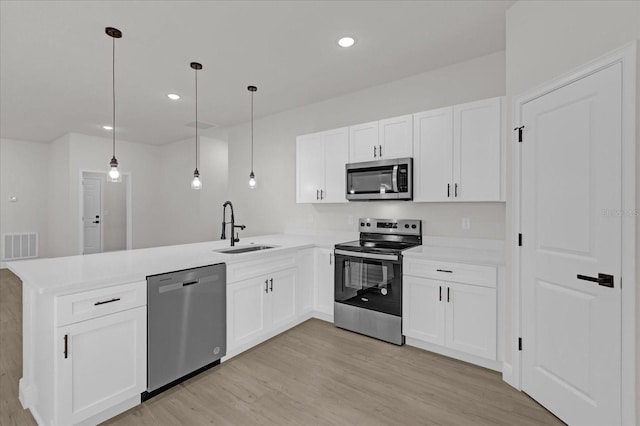 kitchen with sink, decorative light fixtures, kitchen peninsula, and appliances with stainless steel finishes