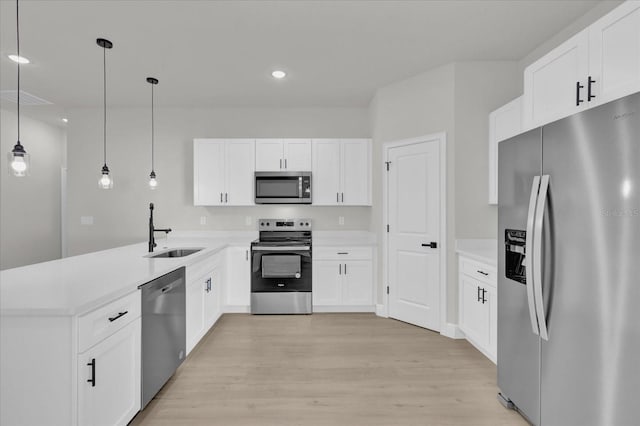 kitchen featuring sink, hanging light fixtures, light wood-type flooring, stainless steel appliances, and white cabinets