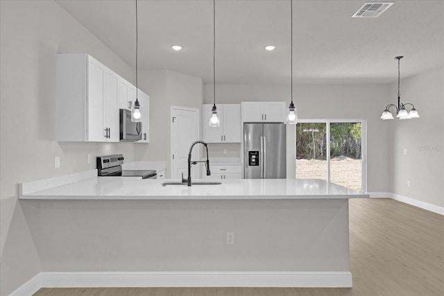 kitchen featuring sink, white cabinetry, kitchen peninsula, pendant lighting, and stainless steel appliances