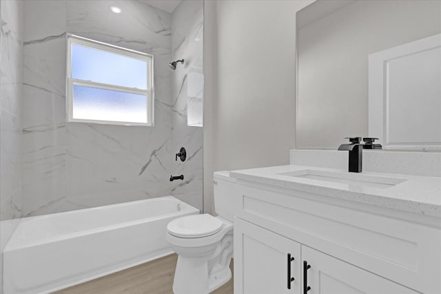 full bathroom with tiled shower / bath combo, vanity, hardwood / wood-style floors, and toilet