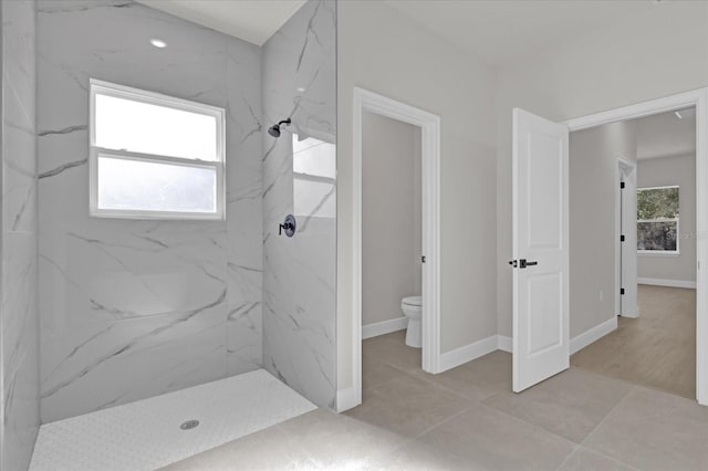 bathroom with a tile shower and toilet