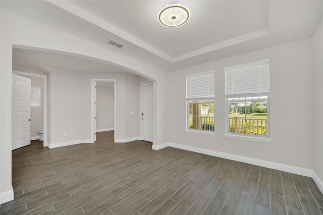 empty room featuring a tray ceiling and dark hardwood / wood-style floors