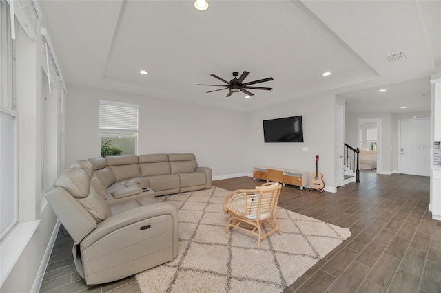 living room with a tray ceiling and ceiling fan