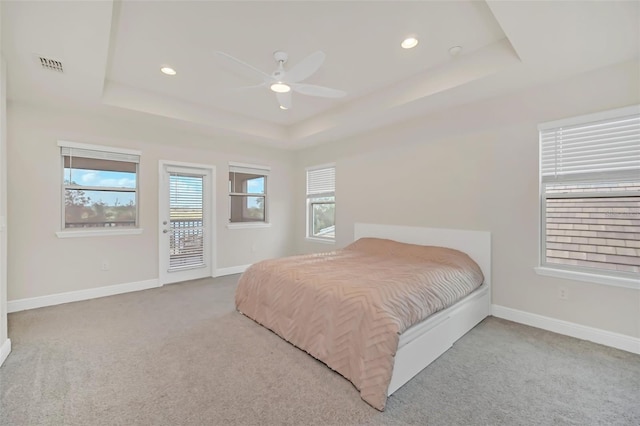 bedroom with ceiling fan, light colored carpet, a tray ceiling, and access to outside