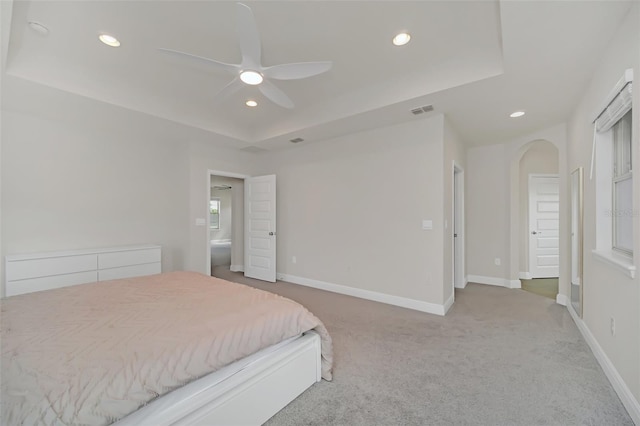 carpeted bedroom with ceiling fan and a tray ceiling