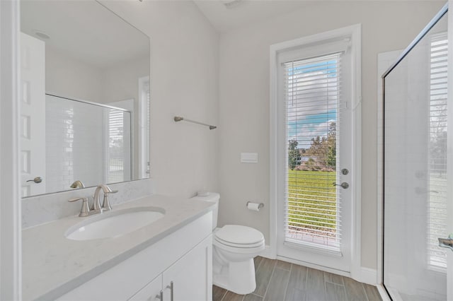 bathroom featuring a shower with door, vanity, and toilet