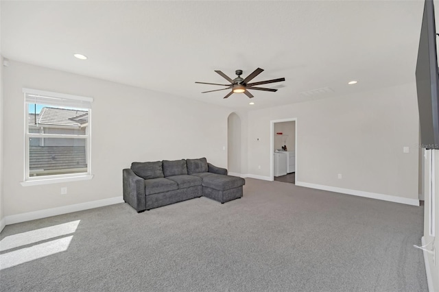 carpeted living room with ceiling fan and washer and dryer