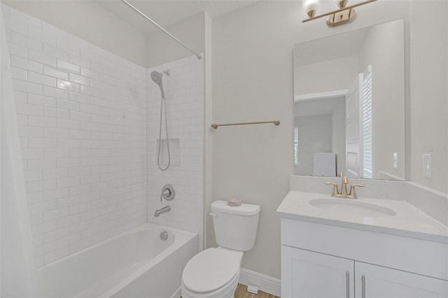 full bathroom featuring vanity, tiled shower / bath, and toilet