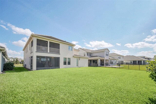 rear view of property featuring a sunroom and a yard