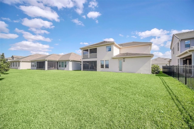 back of property featuring a sunroom and a lawn