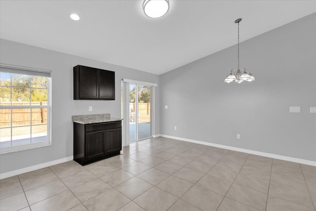 unfurnished living room with an inviting chandelier, vaulted ceiling, and light tile patterned flooring