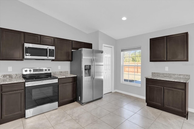 kitchen with dark brown cabinets, vaulted ceiling, light tile patterned flooring, and appliances with stainless steel finishes