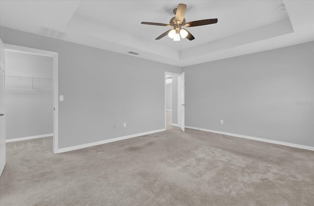 carpeted spare room with ceiling fan and a tray ceiling