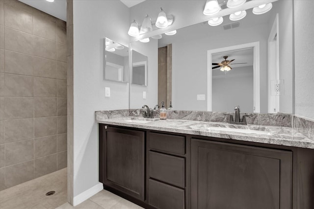 bathroom with tile patterned flooring, vanity, a tile shower, and ceiling fan