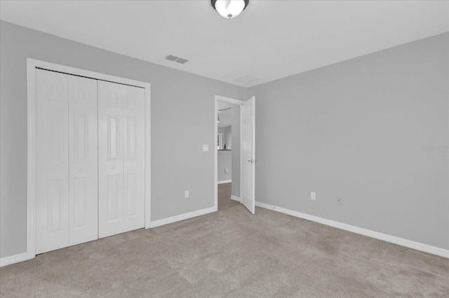 unfurnished bedroom featuring light colored carpet and a closet