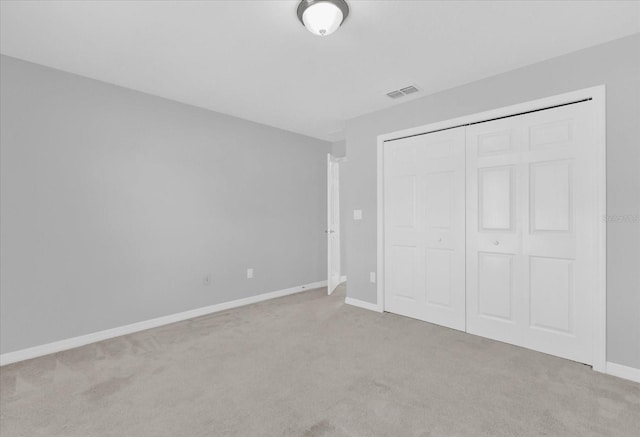 unfurnished bedroom with light carpet and a closet