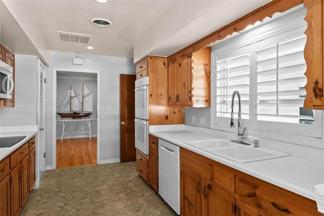 625 Brechin Dr, Winter Park, FL 32792 - kitchen with dishwashing machine, a sink, double oven, brown cabinetry, and light countertops