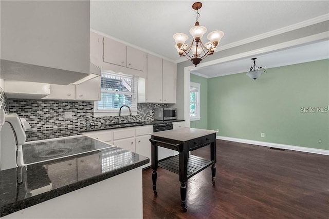 kitchen featuring decorative light fixtures, tasteful backsplash, black dishwasher, dark hardwood / wood-style flooring, and ornamental molding