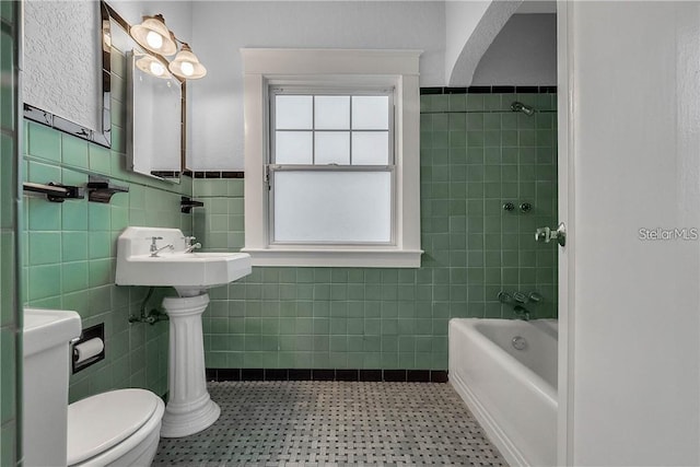 bathroom featuring  shower combination, tile walls, tile patterned floors, and toilet