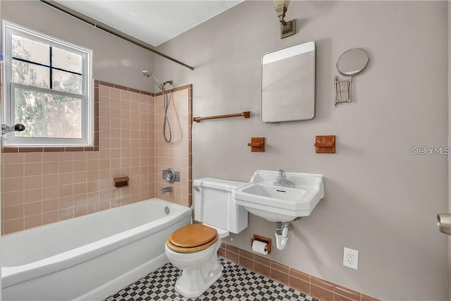 full bathroom featuring tile patterned flooring, tiled shower / bath combo, sink, and toilet