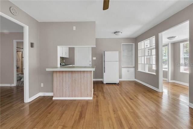 kitchen with white refrigerator, ceiling fan, kitchen peninsula, and light wood-type flooring