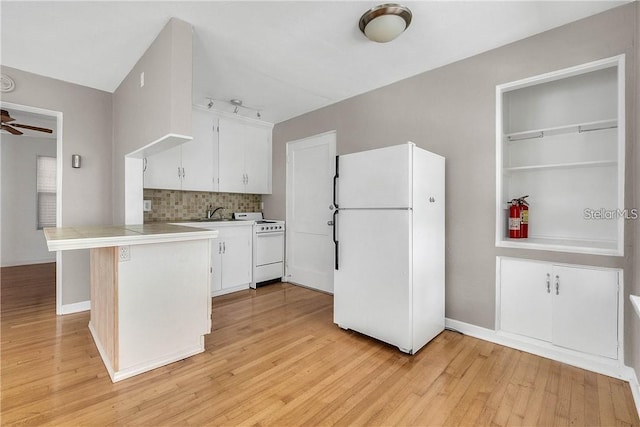 kitchen with white appliances, light hardwood / wood-style flooring, white cabinetry, tasteful backsplash, and kitchen peninsula