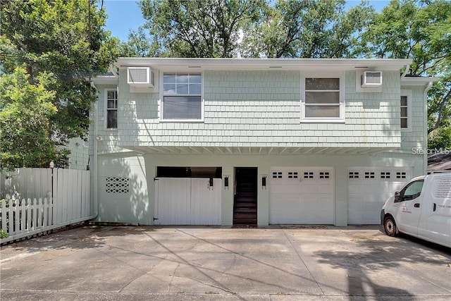 view of front of home featuring a garage and an AC wall unit