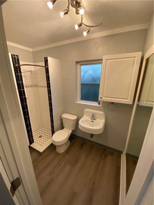 bathroom featuring tiled shower, toilet, sink, a textured ceiling, and hardwood / wood-style flooring