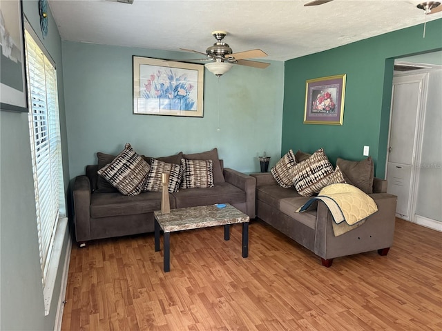 living room with ceiling fan, a textured ceiling, and light hardwood / wood-style floors