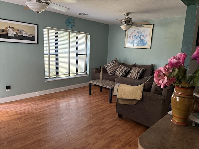 living room with hardwood / wood-style floors, a textured ceiling, and ceiling fan