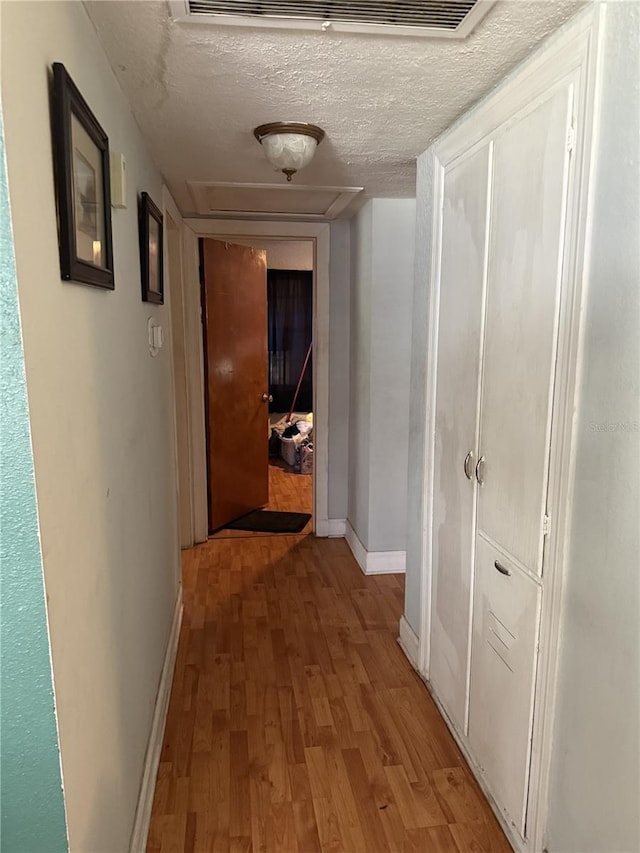 hall featuring light hardwood / wood-style flooring and a textured ceiling