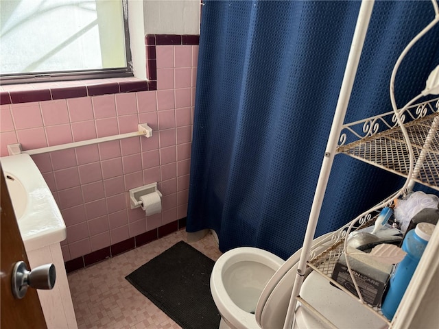 bathroom with a shower with curtain, tile walls, and toilet