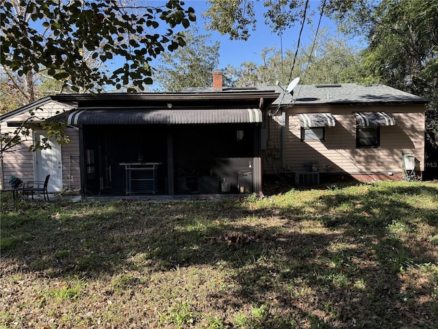 rear view of house featuring central AC and a yard