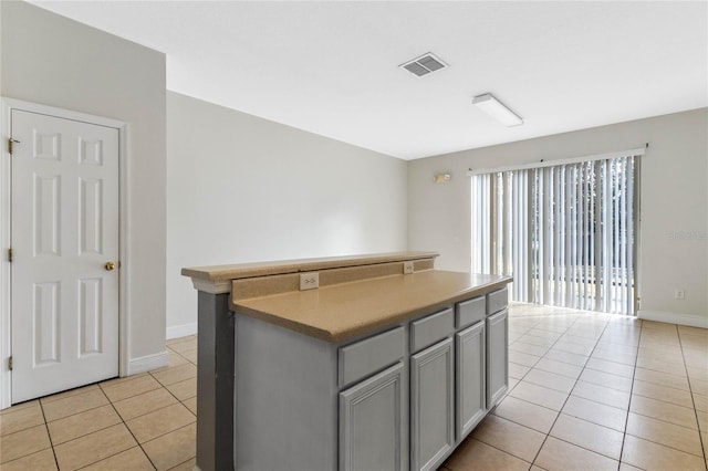 kitchen featuring gray cabinets, a center island, and light tile patterned floors