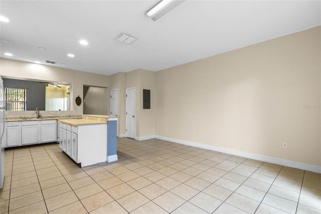 kitchen featuring electric panel, light tile patterned floors, white cabinets, and kitchen peninsula