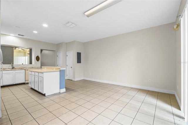 kitchen featuring dishwasher, white cabinets, a center island, light tile patterned floors, and electric panel