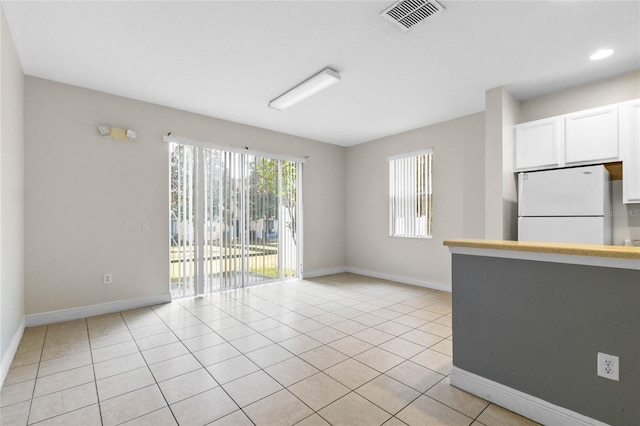 interior space with white cabinetry, light tile patterned floors, and white refrigerator