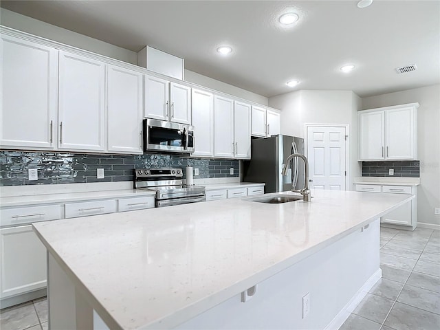 kitchen with stainless steel appliances, a center island with sink, and white cabinets