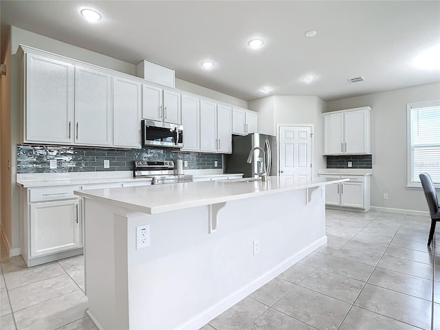 kitchen with a kitchen island with sink, sink, white cabinets, and appliances with stainless steel finishes