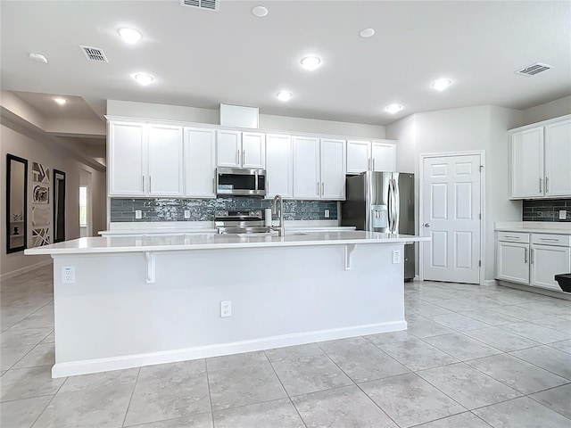 kitchen featuring appliances with stainless steel finishes, a kitchen island with sink, and a kitchen bar