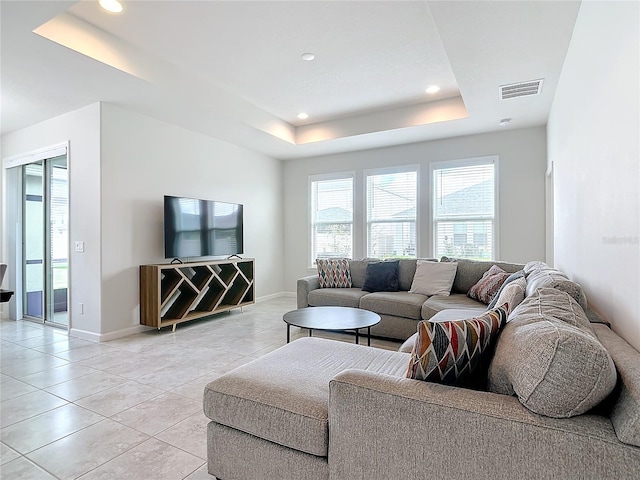 living room with a raised ceiling and light tile patterned flooring