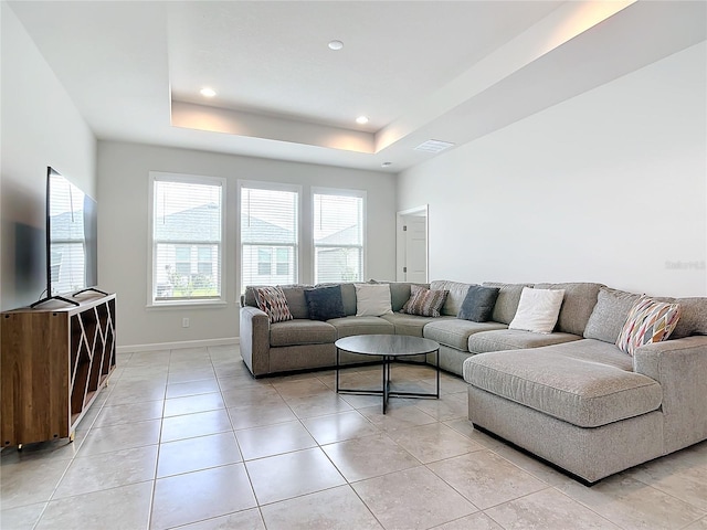 living room featuring light tile patterned flooring and a tray ceiling