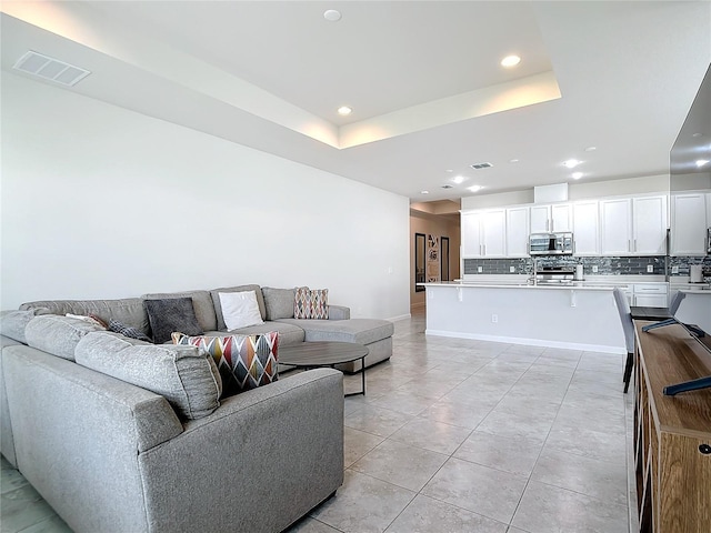 living room featuring light tile patterned floors and a tray ceiling