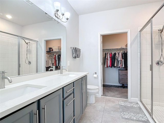 bathroom featuring tile patterned flooring, vanity, a shower with shower door, and toilet