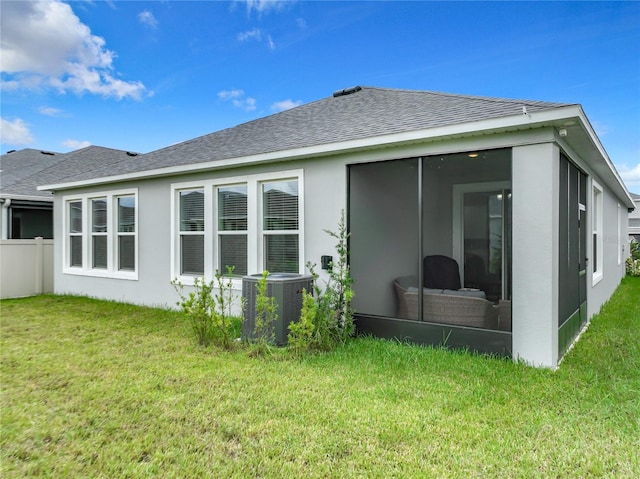 rear view of house with central AC, a sunroom, and a lawn