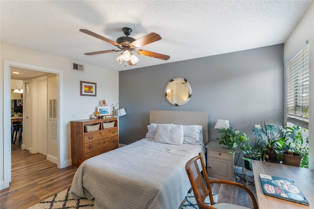 bedroom featuring ceiling fan, hardwood / wood-style floors, and a textured ceiling