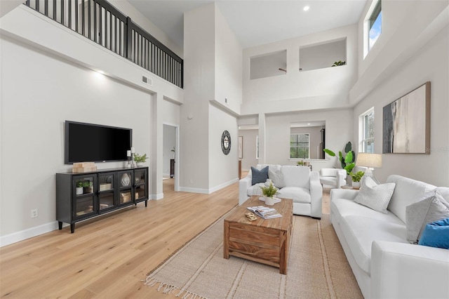 living room with plenty of natural light, wood-type flooring, and a high ceiling